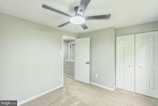 unfurnished bedroom with baseboards, a ceiling fan, carpet, and a closet