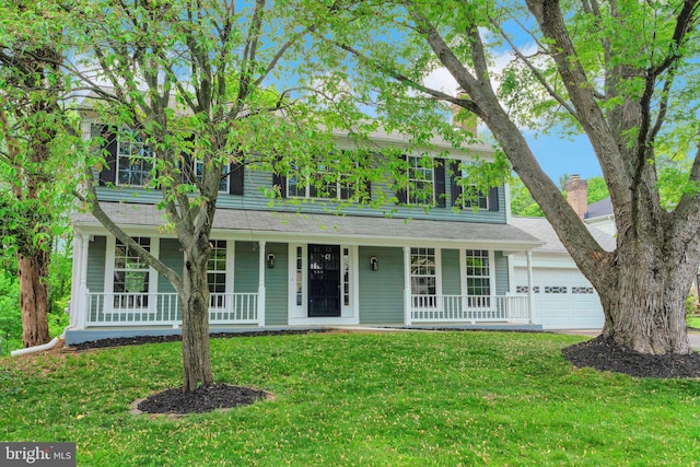 colonial-style house with an attached garage, a front lawn, and covered porch