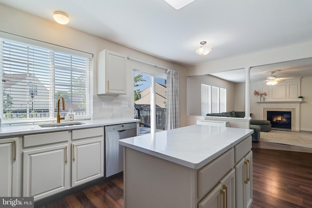 kitchen featuring a sink, a fireplace, dark wood-style flooring, a center island, and stainless steel dishwasher