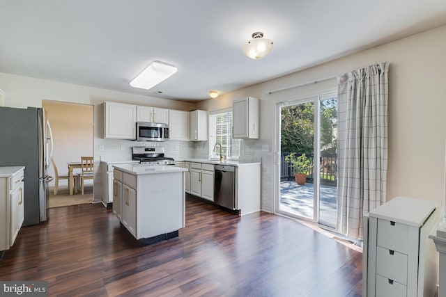 kitchen with light countertops, appliances with stainless steel finishes, a sink, and a kitchen island