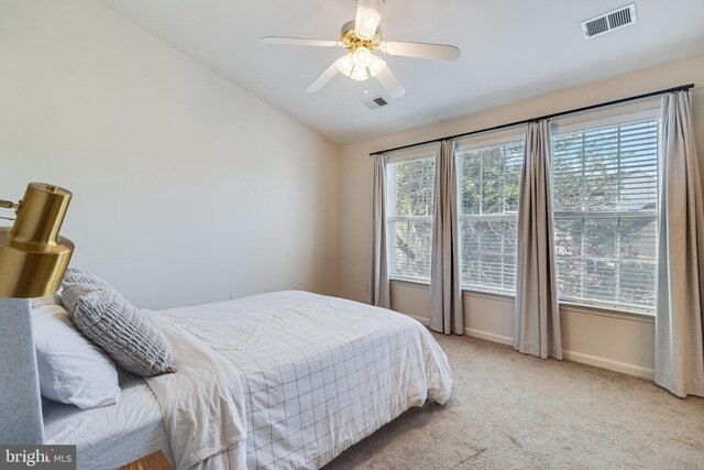 bedroom with vaulted ceiling, light carpet, baseboards, and visible vents