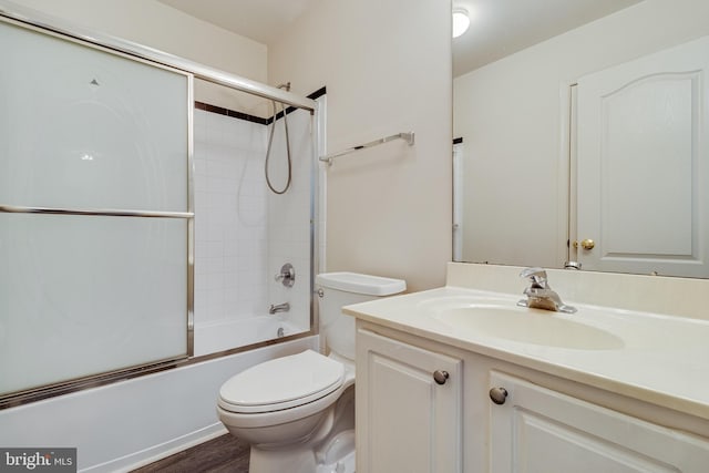 bathroom with vanity, toilet, shower / bath combination with glass door, and wood finished floors