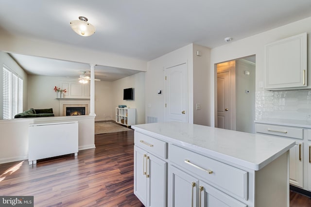 kitchen with light countertops, dark wood-style flooring, ceiling fan, and a warm lit fireplace