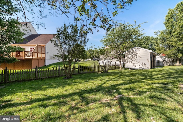 view of yard with an outdoor structure, a deck, a fenced backyard, and a shed