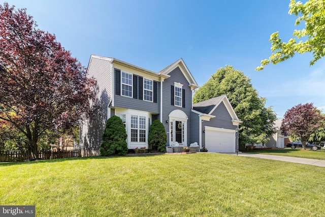 colonial home featuring a front lawn, concrete driveway, fence, and a garage