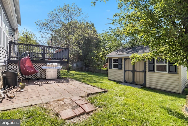 view of yard with a storage shed, a patio, fence, a wooden deck, and an outbuilding