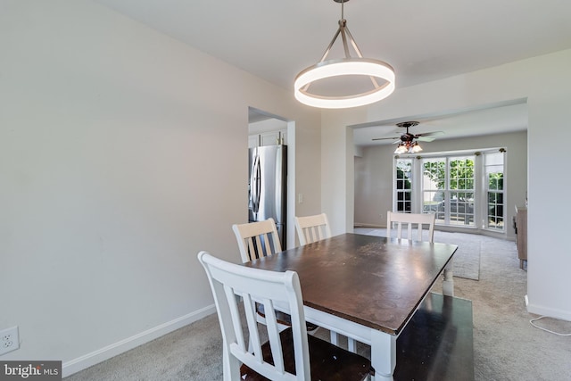 dining room with light colored carpet, baseboards, and a ceiling fan