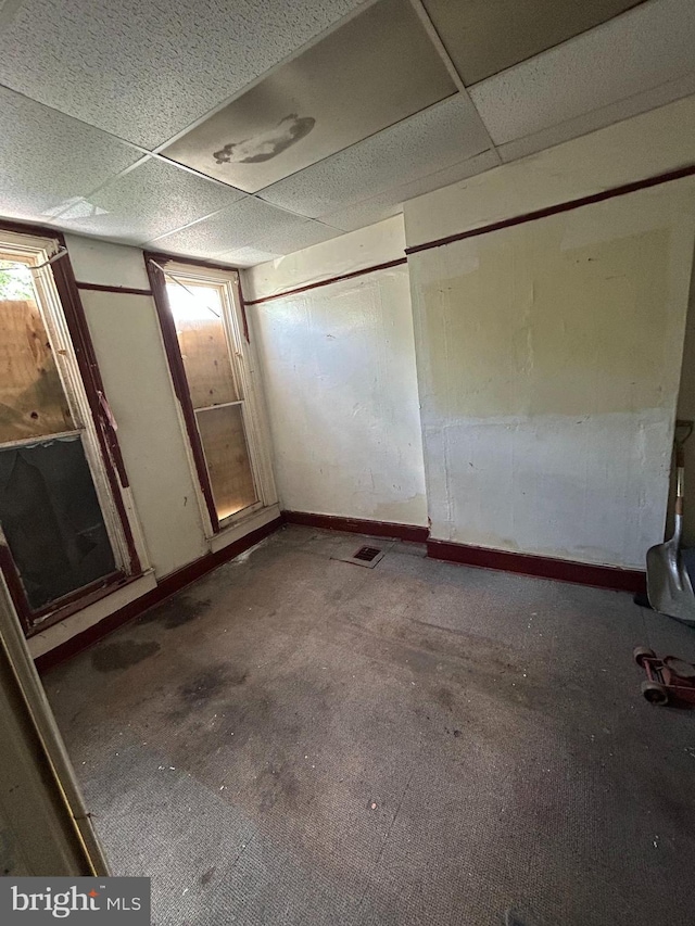 unfurnished bedroom with baseboards and a paneled ceiling
