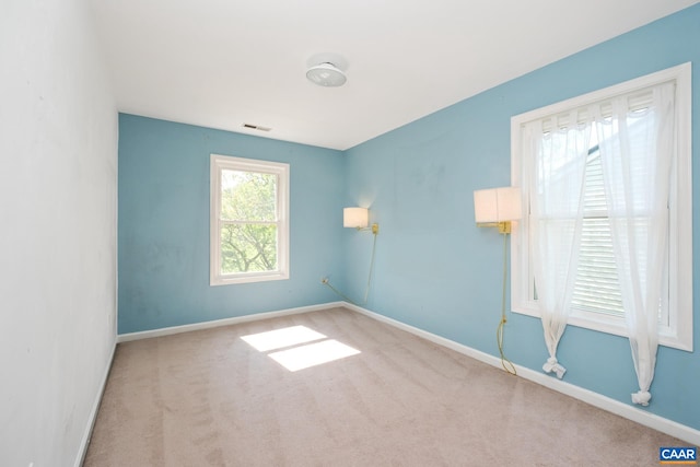 carpeted spare room featuring baseboards and visible vents