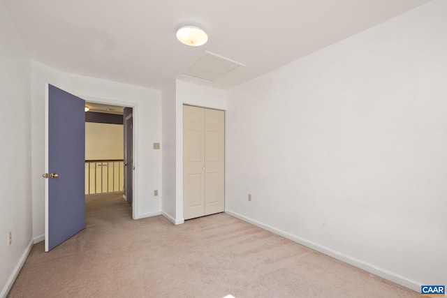 unfurnished bedroom with attic access, baseboards, carpet, and a closet