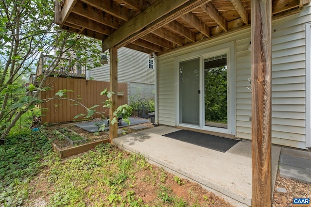 view of exterior entry featuring a patio area and fence