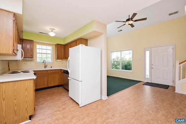 kitchen featuring dishwasher, a sink, baseboards, freestanding refrigerator, and light floors