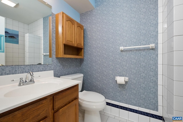bathroom with toilet, tile walls, and vanity
