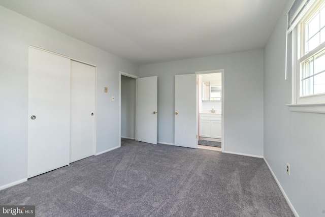 unfurnished bedroom featuring carpet floors, baseboards, ensuite bathroom, and a closet