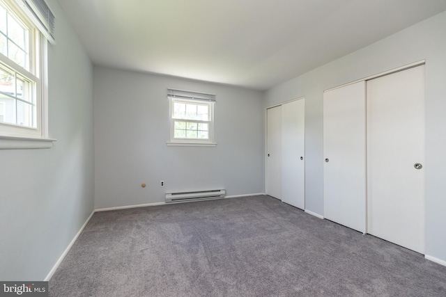 unfurnished bedroom featuring carpet, multiple closets, baseboards, and baseboard heating
