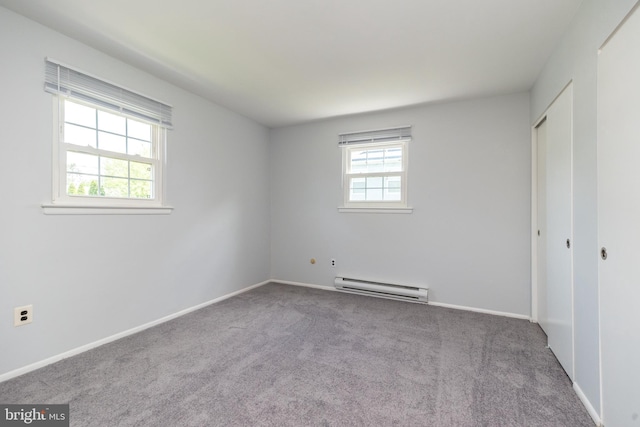 unfurnished bedroom featuring a closet, baseboards, baseboard heating, and carpet flooring