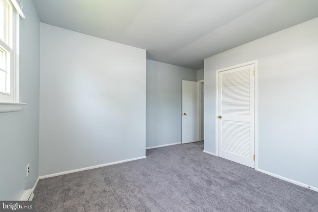 carpeted empty room featuring baseboards