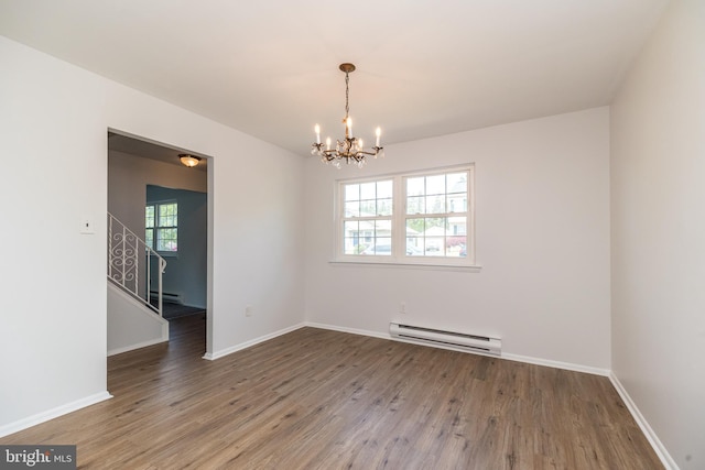 spare room with wood finished floors, a chandelier, baseboard heating, and a wealth of natural light