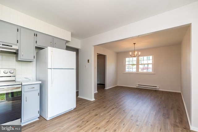 kitchen with baseboard heating, stainless steel range with electric cooktop, freestanding refrigerator, a notable chandelier, and under cabinet range hood