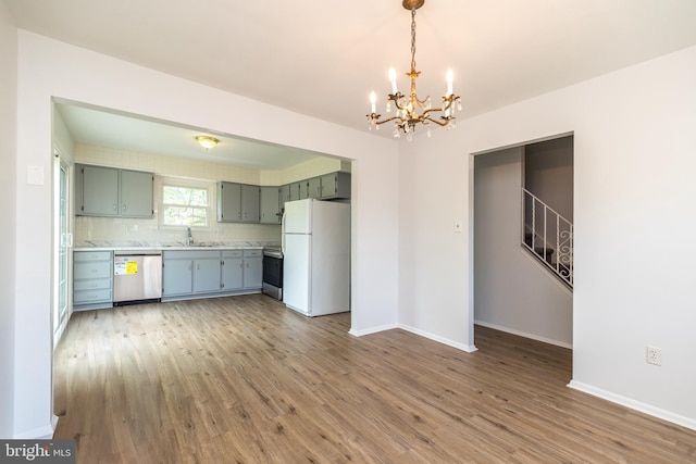 kitchen with an inviting chandelier, wood finished floors, light countertops, a sink, and stainless steel appliances