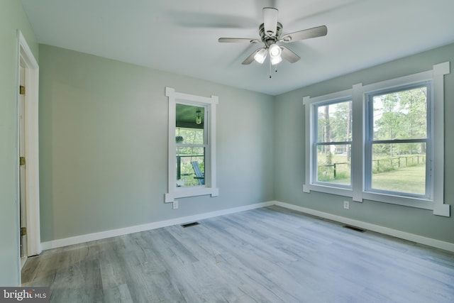 empty room featuring plenty of natural light, wood finished floors, and baseboards