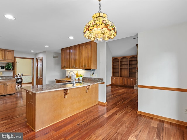 12553 Fawn Dr, Laurel, DE 19956 - kitchen featuring a sink, light stone countertops, brown cabinetry, dark wood finished floors, and a peninsula