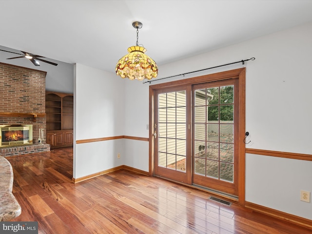12553 Fawn Dr, Laurel, DE 19956 - unfurnished dining area with hardwood / wood-style floors, baseboards, ceiling fan, and a brick fireplace