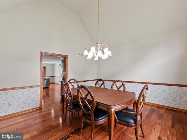 12553 Fawn Dr, Laurel, DE 19956 - dining area featuring wood finished floors, wallpapered walls, a chandelier, baseboards, and high vaulted ceiling