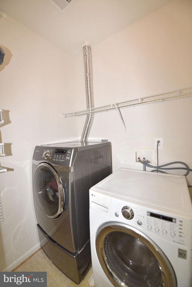 washroom featuring laundry area, baseboards, visible vents, and washing machine and clothes dryer