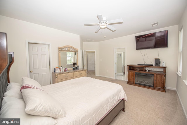 bedroom featuring baseboards, ensuite bathroom, visible vents, and light carpet