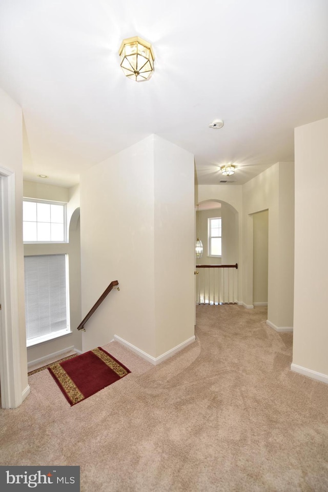 interior space with baseboards, arched walkways, and carpet flooring