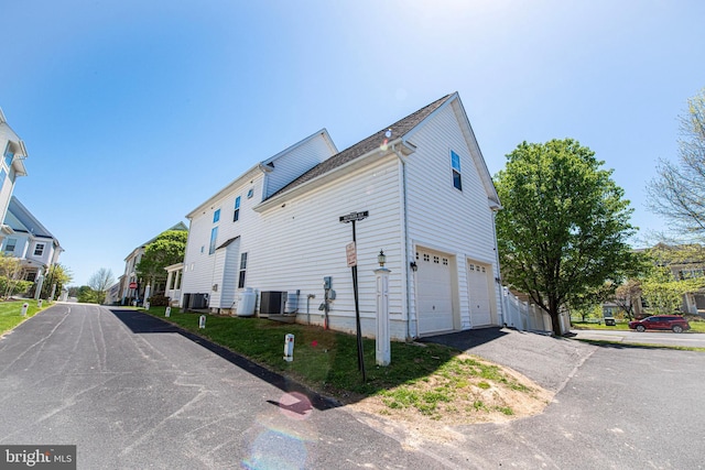 view of property exterior with a garage, central AC, and aphalt driveway