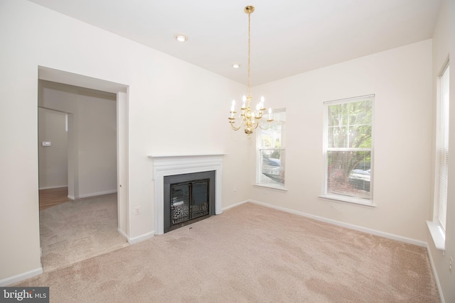 unfurnished living room with a glass covered fireplace, baseboards, carpet flooring, and a chandelier