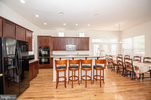kitchen with light countertops, recessed lighting, light wood finished floors, and black appliances
