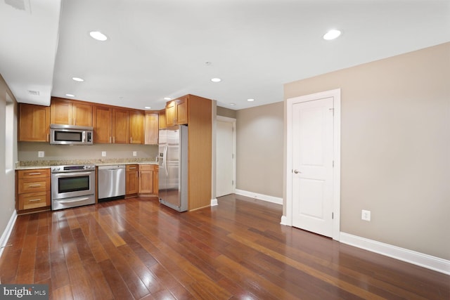 kitchen featuring brown cabinetry, appliances with stainless steel finishes, baseboards, dark wood-style floors, and recessed lighting