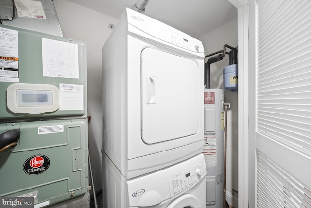clothes washing area featuring laundry area, water heater, and stacked washer / drying machine