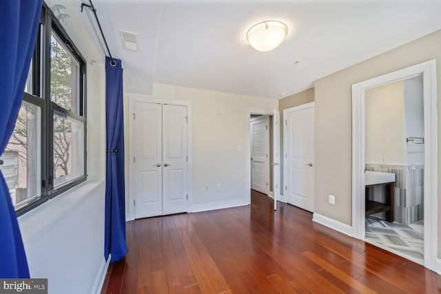 unfurnished bedroom with baseboards, wood finished floors, and visible vents