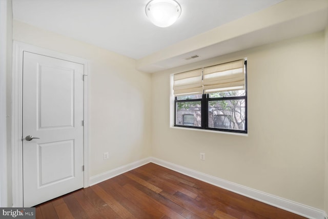 spare room featuring baseboards, visible vents, and dark wood-type flooring
