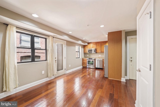 kitchen featuring dark wood-style flooring, appliances with stainless steel finishes, light countertops, baseboards, and recessed lighting