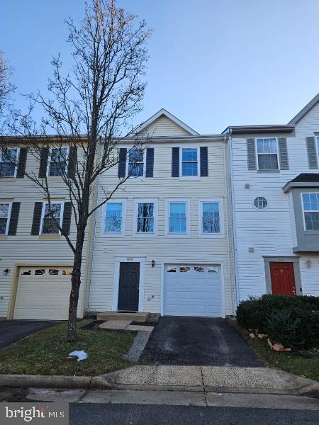 townhome / multi-family property with an attached garage and aphalt driveway