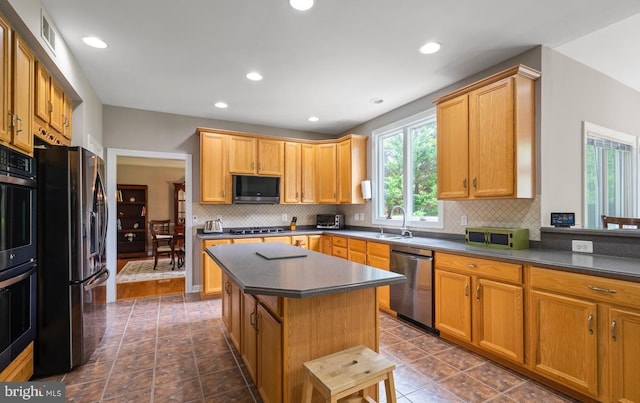 kitchen with a sink, appliances with stainless steel finishes, a wealth of natural light, and dark countertops