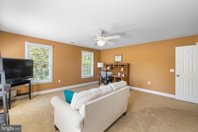 living room featuring ceiling fan, light carpet, and baseboards