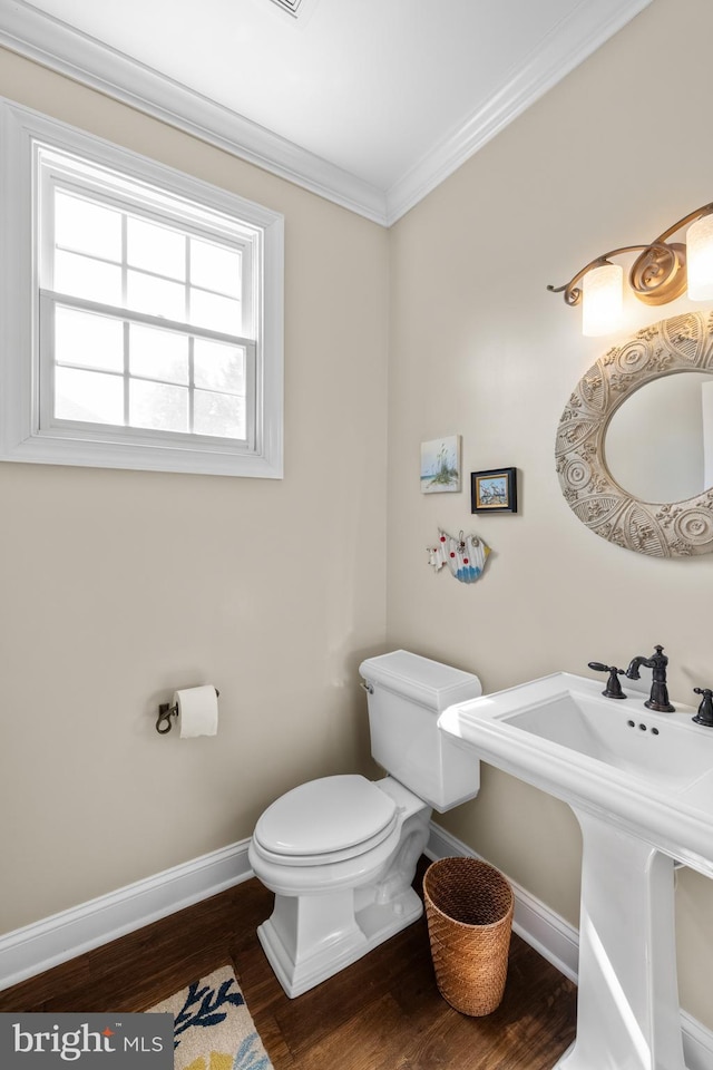 half bath featuring baseboards, crown molding, wood finished floors, and toilet