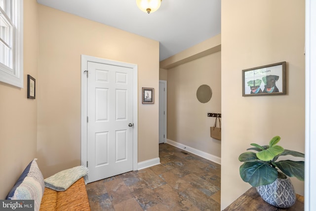 entryway with stone tile flooring and baseboards