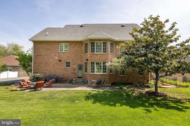 back of house featuring a lawn, a patio area, brick siding, and entry steps