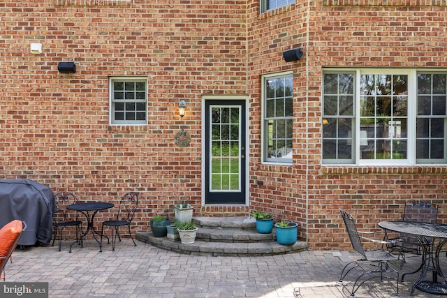 entrance to property featuring brick siding, a patio, and outdoor dining space
