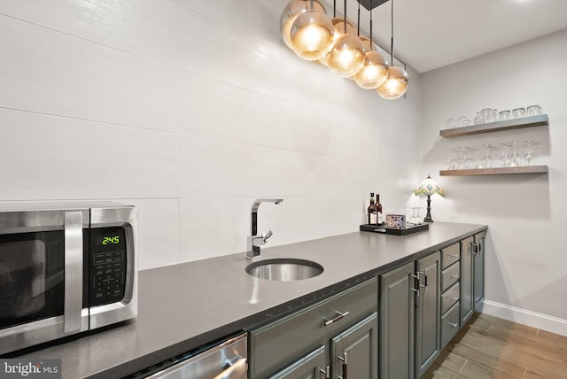 12019 Wandabury Rd, Oakton, VA 22124 - indoor wet bar featuring appliances with stainless steel finishes, baseboards, light wood-style floors, and pendant lighting