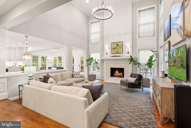12019 Wandabury Rd, Oakton, VA 22124 - living room featuring a high ceiling, wood finished floors, a chandelier, a fireplace with flush hearth, and crown molding