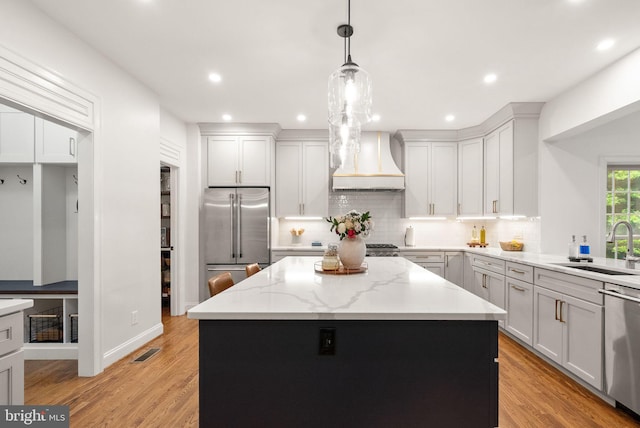 12019 Wandabury Rd, Oakton, VA 22124 - kitchen with stainless steel appliances, custom exhaust hood, a sink, backsplash, and light wood-style floors