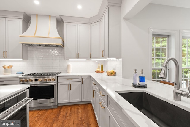 12019 Wandabury Rd, Oakton, VA 22124 - kitchen featuring premium range hood, a sink, high end stove, light stone counters, and wood finished floors